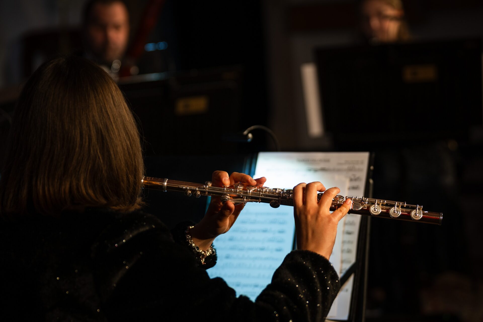person playing flute infront of sheet music